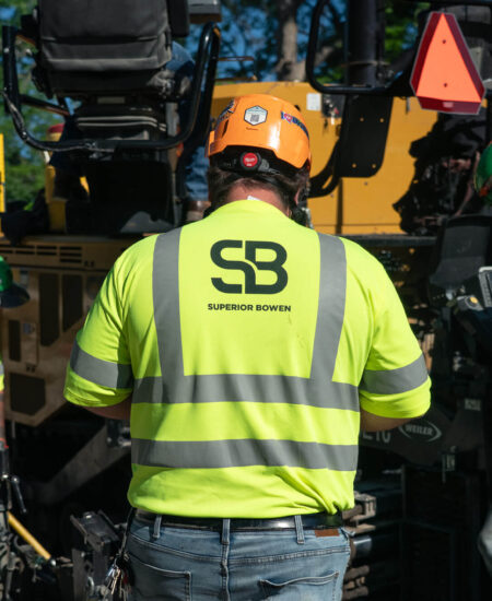 Four workers in SB Superior Bowen shirts operate equipment outdoors.