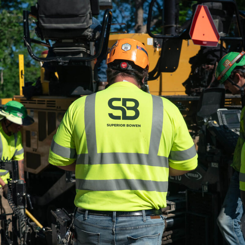 Four workers in SB Superior Bowen shirts operate equipment outdoors.