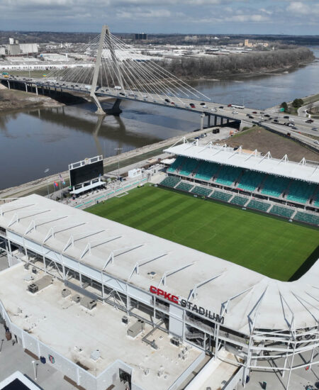 Aerial of CPKC Stadium, green field, parking, river, bridge.
