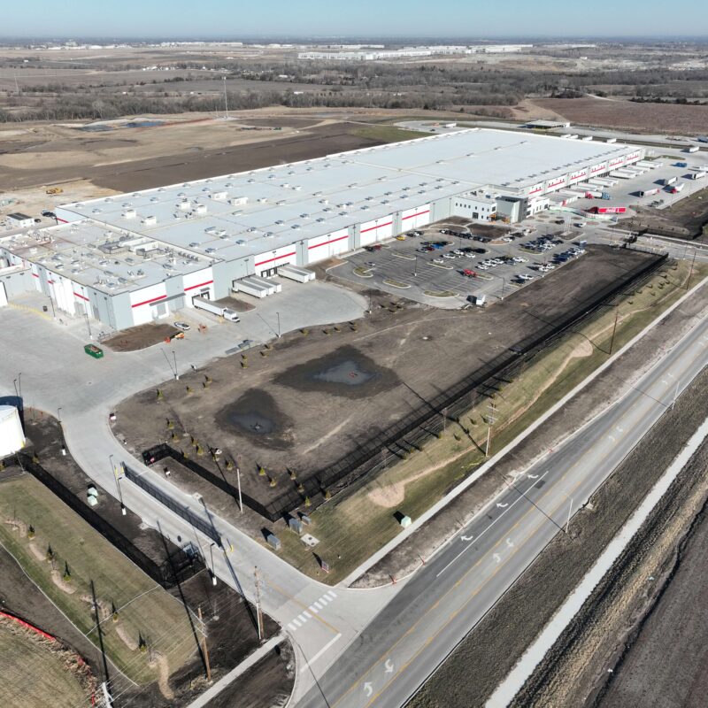 Aerial view of an industrial warehouse with parking lots and fields.
