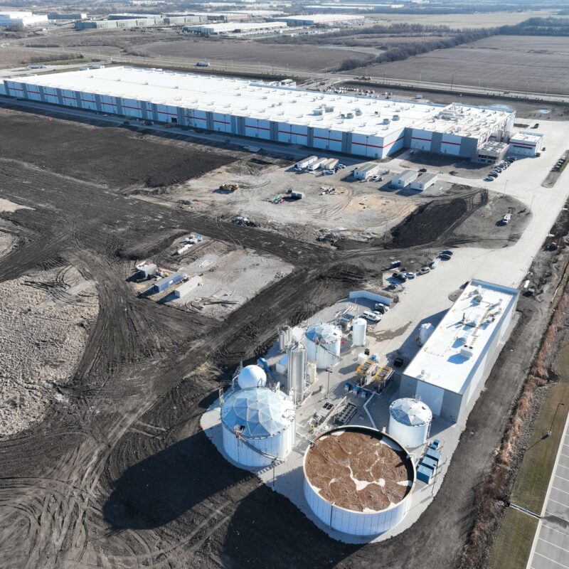 Aerial view of large white industrial buildings and storage tanks.