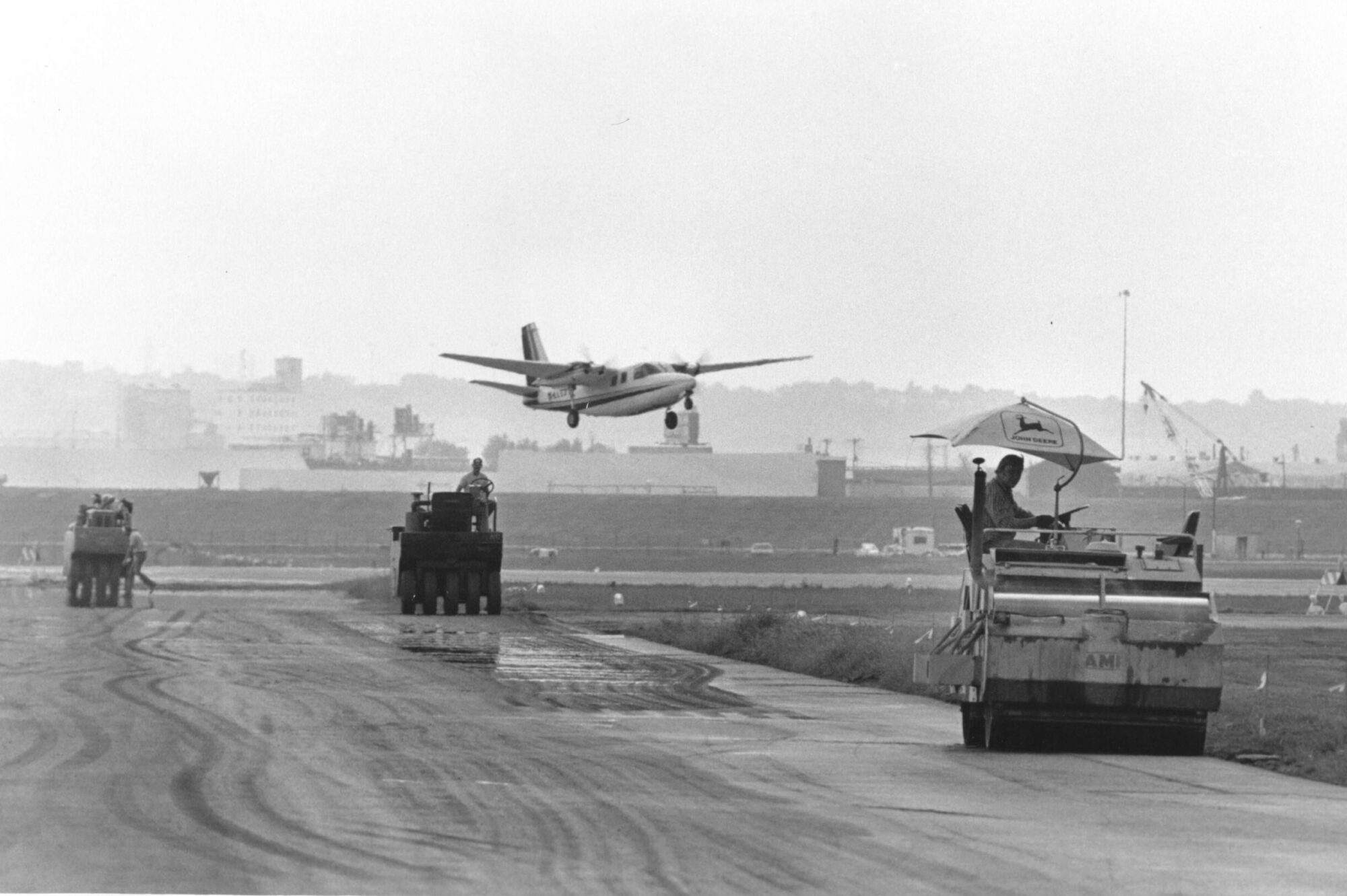 A small plane flies low above a runway being built.