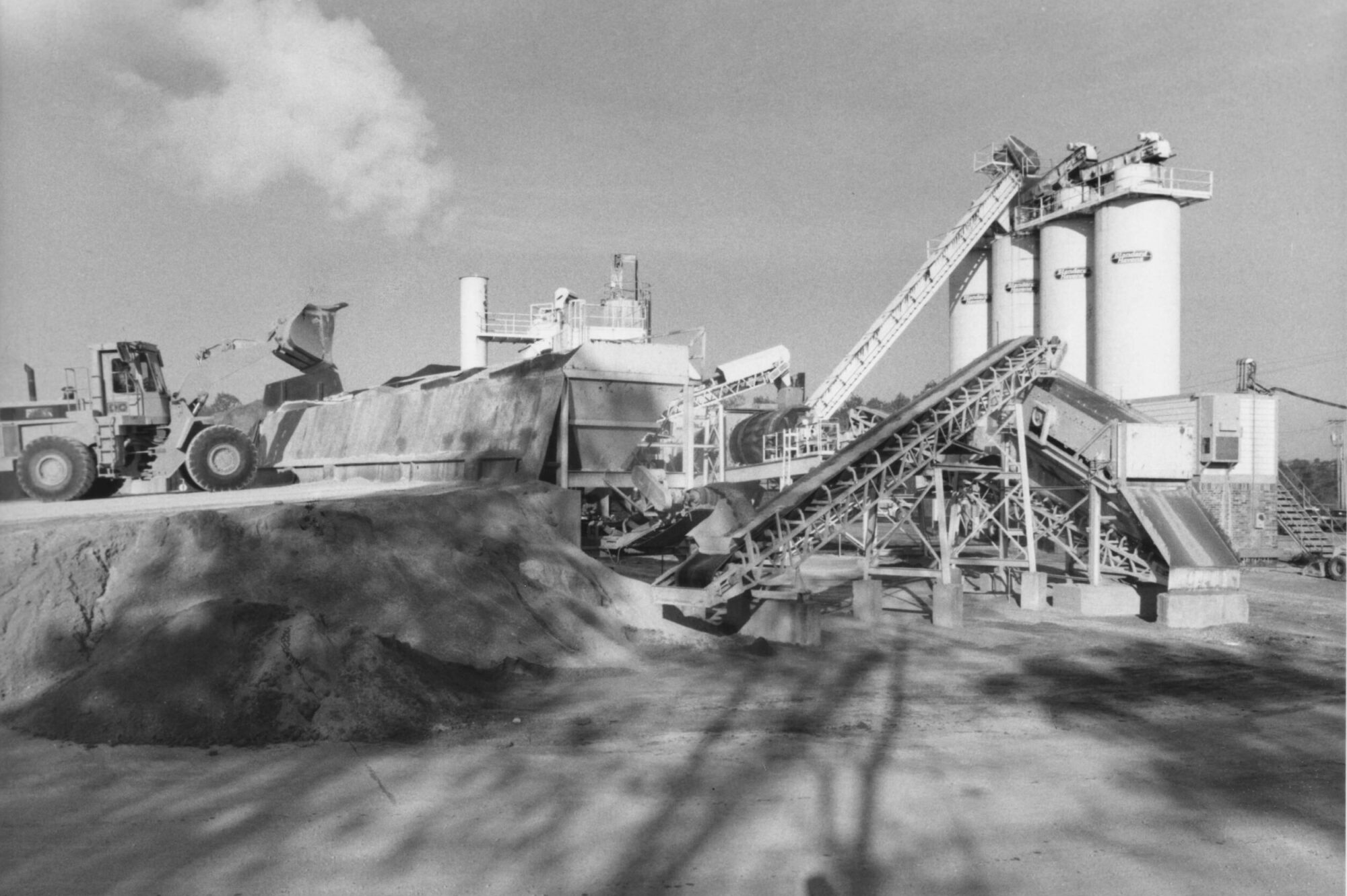Industrial plant in black and white with silos, belts, loader.