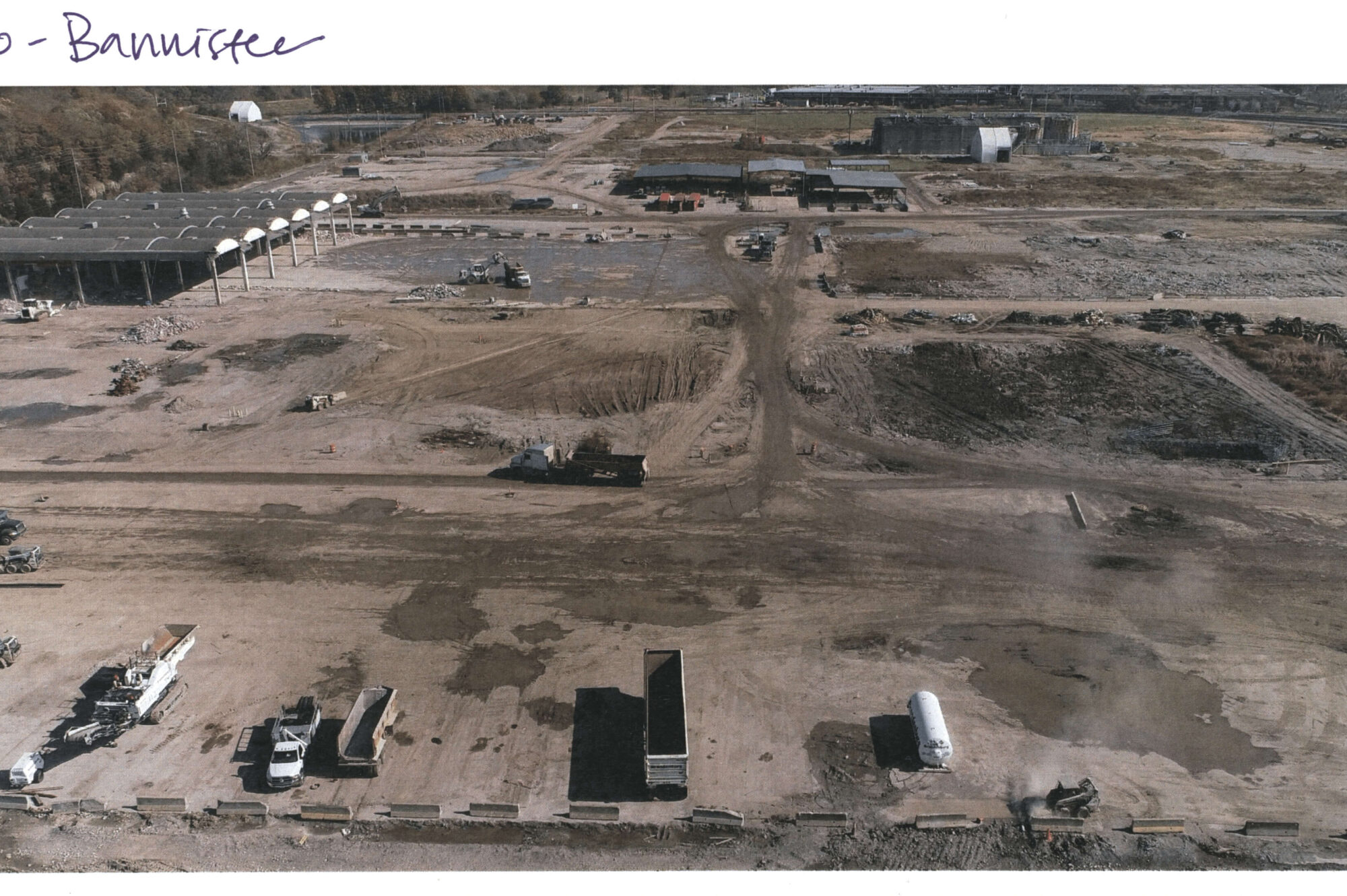 Aerial view of large construction site with vehicles and buildings.