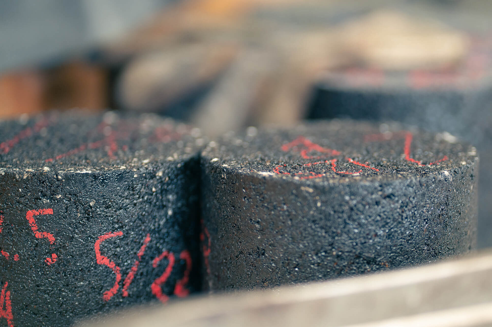 Cylindrical asphalt cores with red markings for road testing.