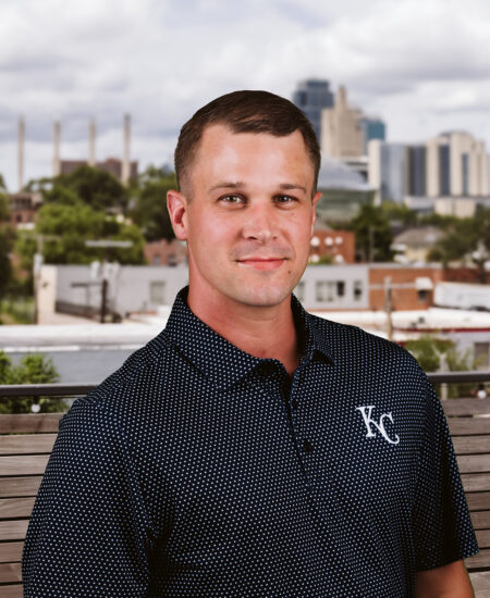 Man in YC polo stands outdoors before a cityscape.