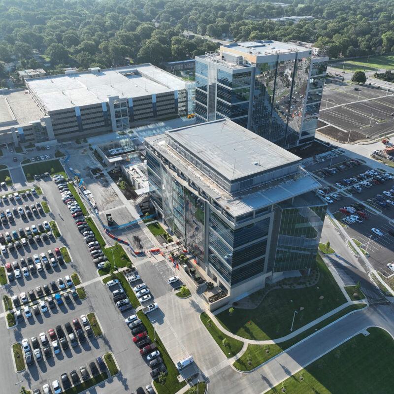 Aerial view of glass office buildings, parking lots, and greenery.