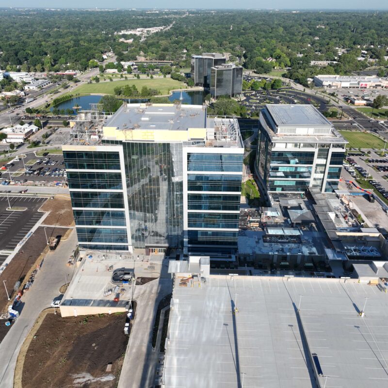 Two office buildings under construction beside a large parking garage.