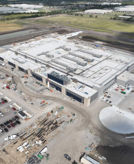 Aerial view of an industrial building under construction and surroundings.