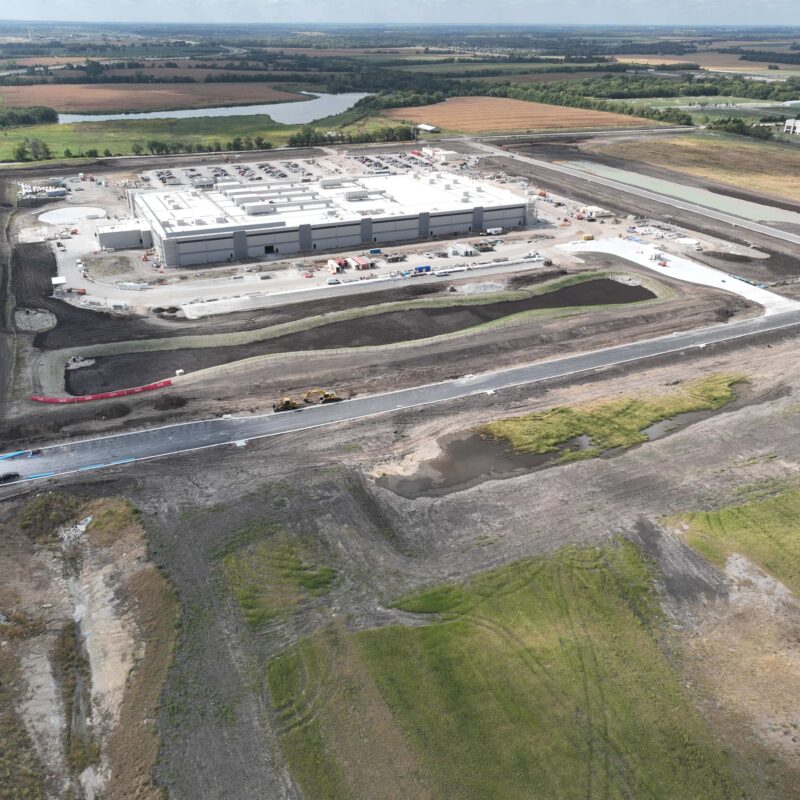Aerial view of industrial building construction amid dirt and machines.