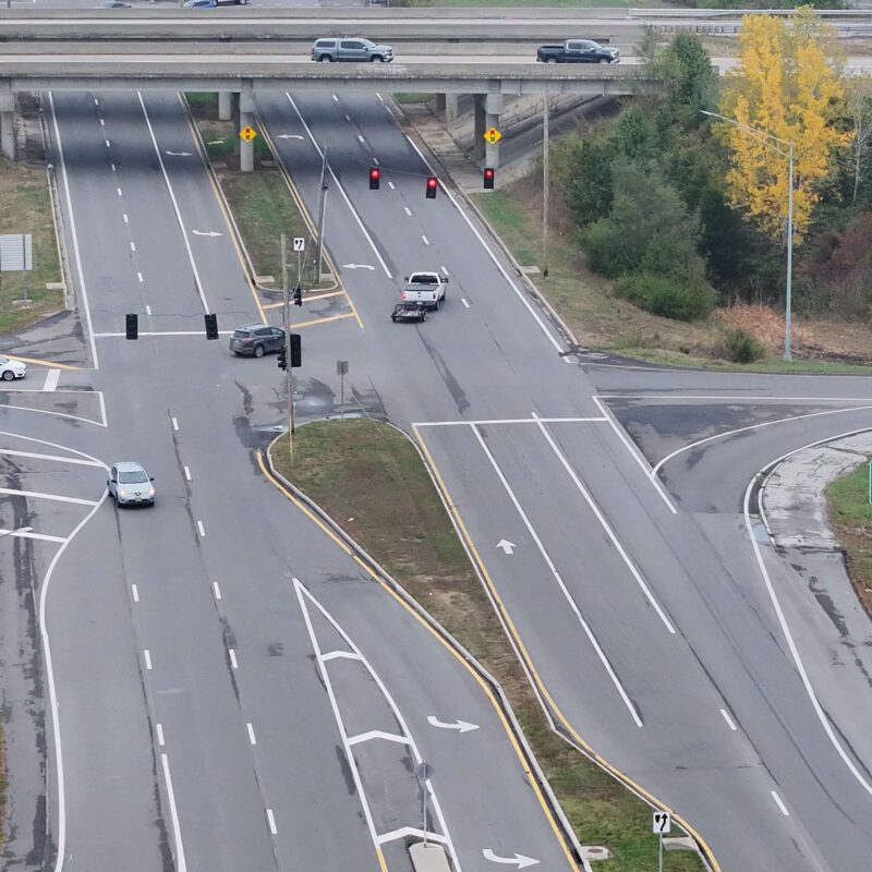 Aerial view of busy intersection, exit sign, trees, overpass.