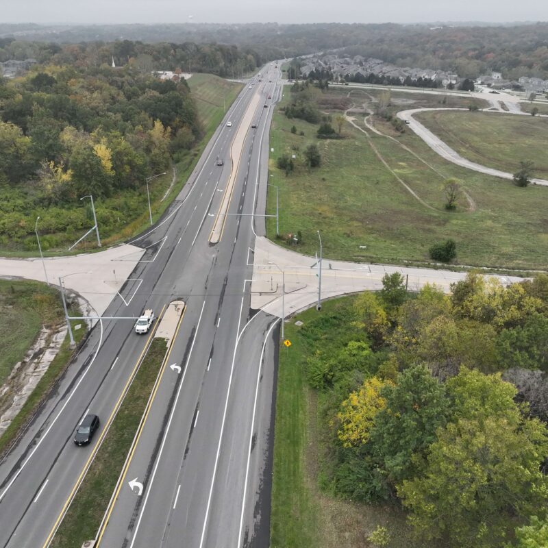 Aerial view of a highway intersection with cars and trees.
