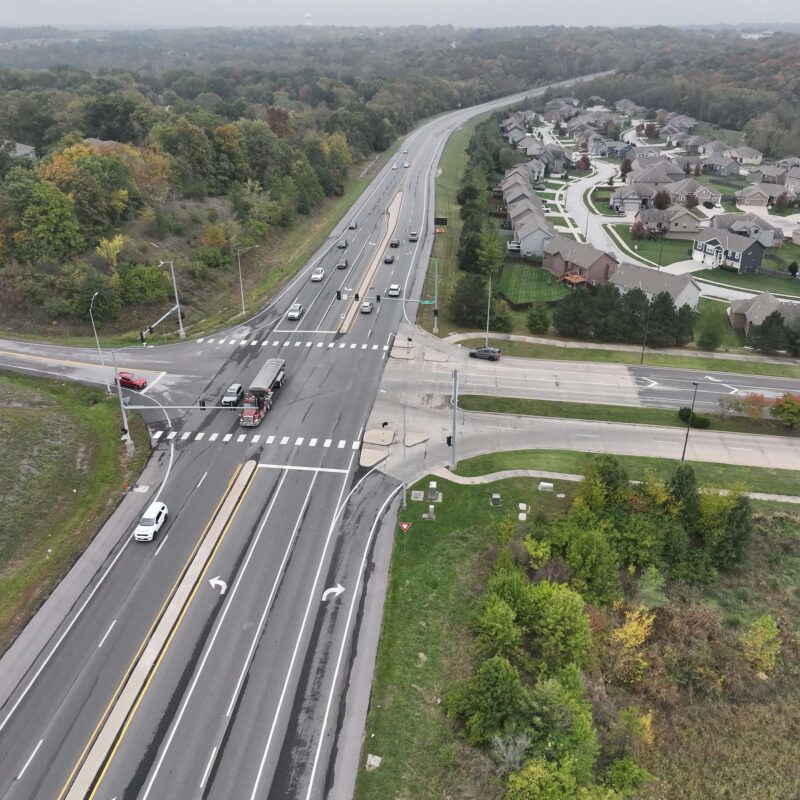 Aerial view of road intersection beside houses and trees.