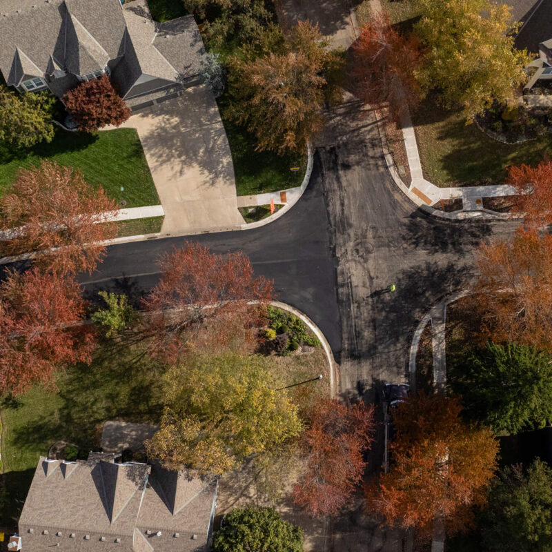 Aerial view of suburban intersection with houses and autumn trees.