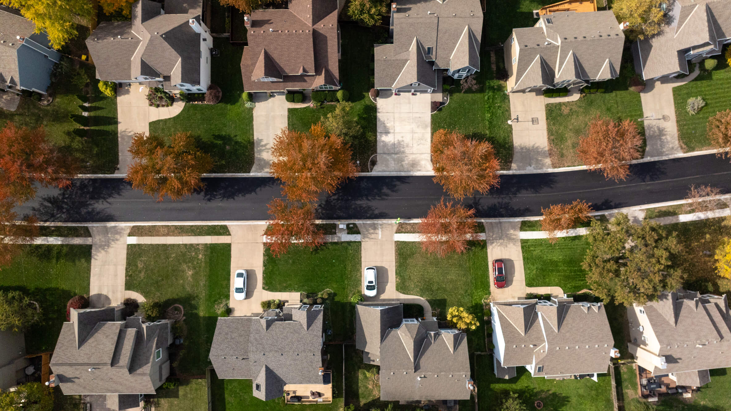 Workers in safety vests repave a street with an asphalt machine.