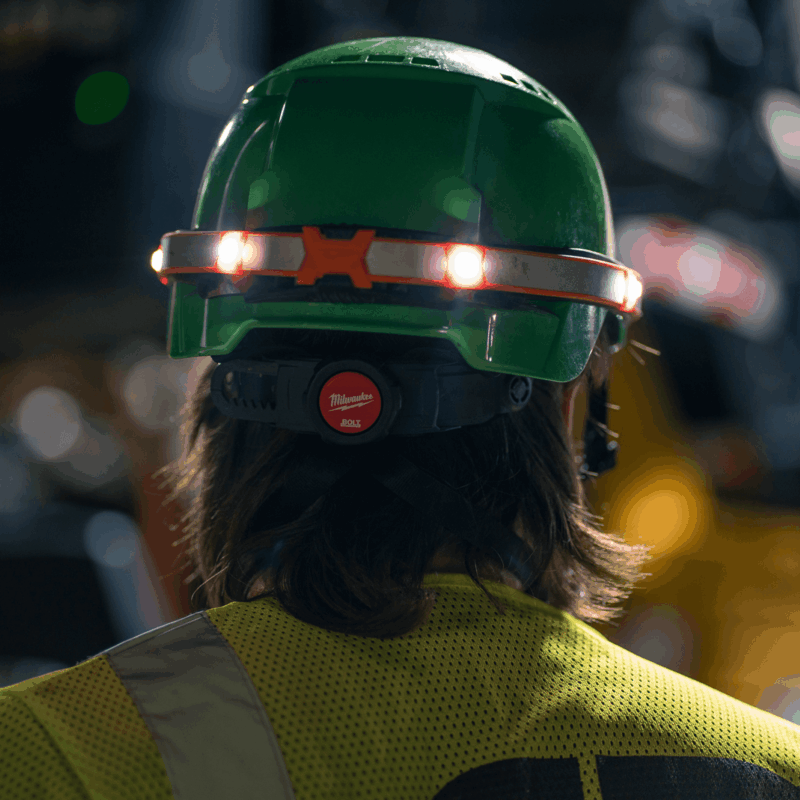 Person in green hard hat with red band, seen from behind.