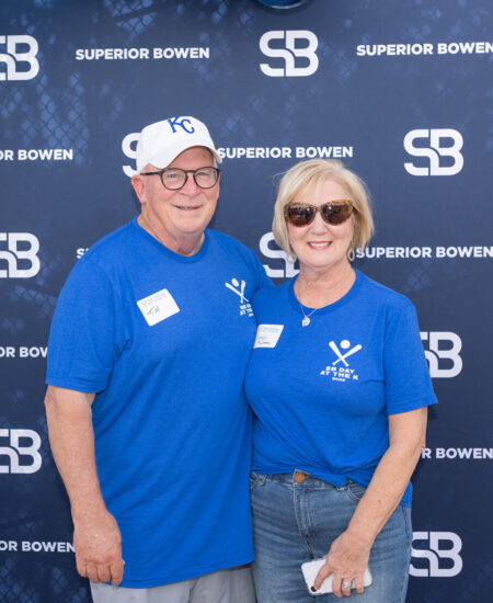 Two people in blue shirts stand before a Superior Bowen banner.